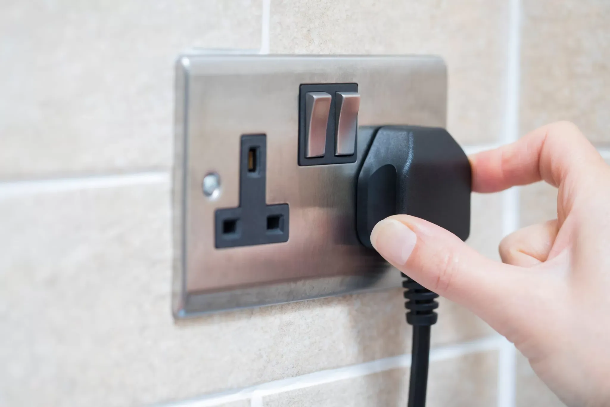 Plug being inserted into a wall socket